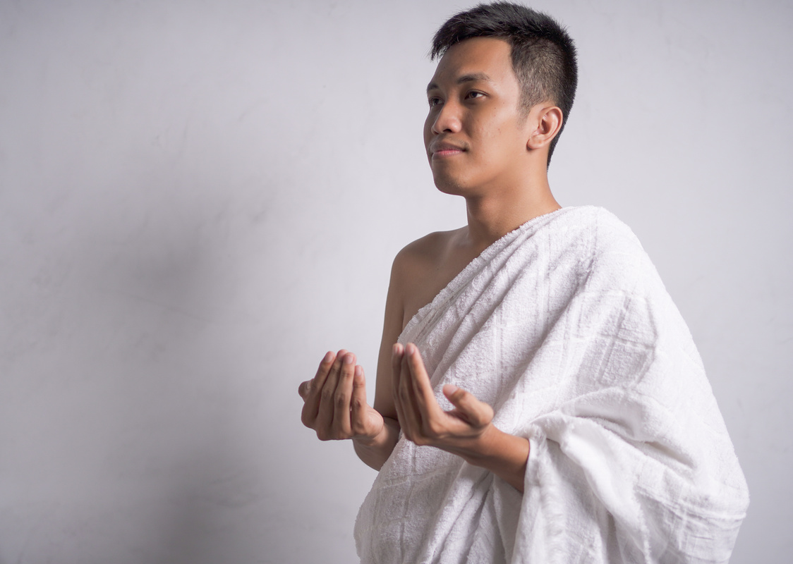 Asian muslim man wearing white ihram clothes show praying